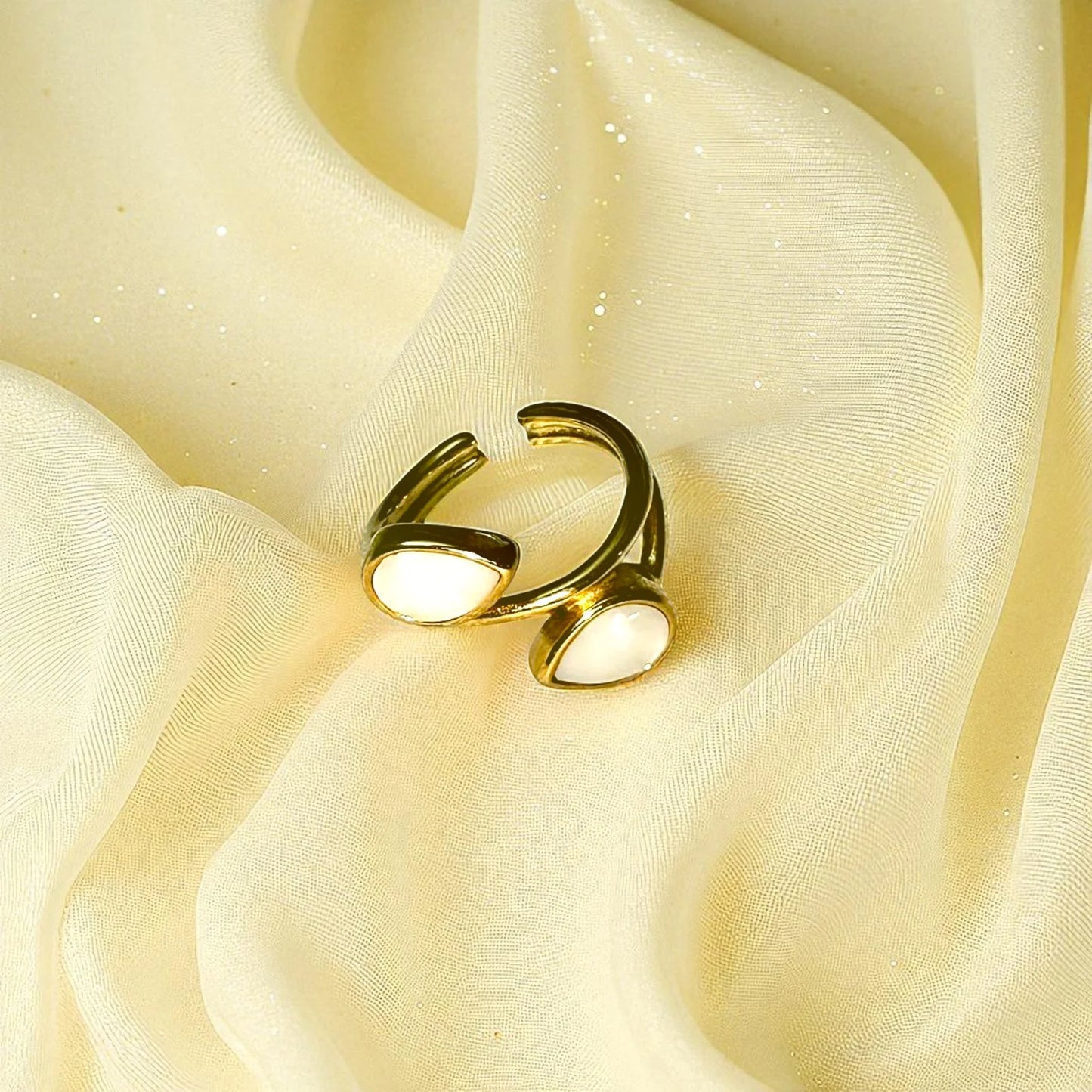 Gold-plated open ring with dual white stones on pink silk background – elegant adjustable jewelry piece for women.Gold-Plated Open Ring with White Stones