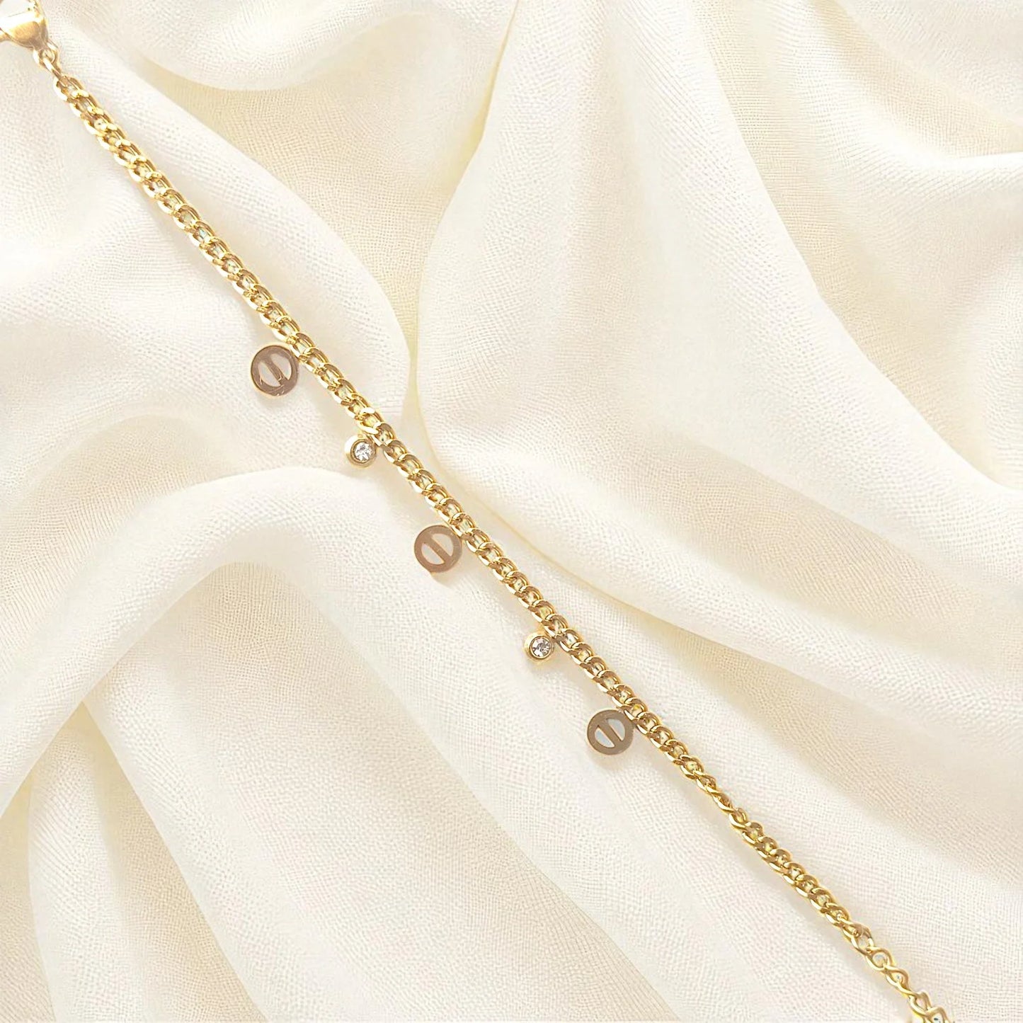 Elegant gold-plated charm bracelet with delicate round charms and cubic stones on wrist